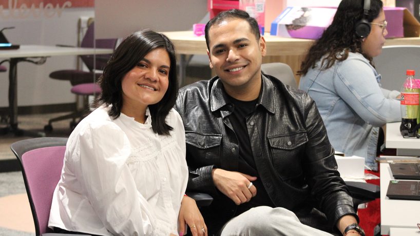 Dos integrantes del equipo sonriendo en su escritorio